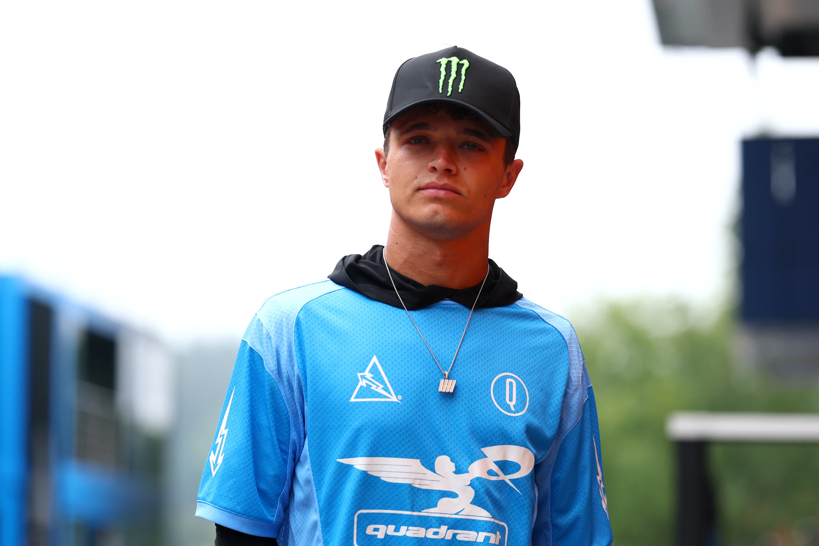 Lando camina por el paddock por delante del Gran Premio de Belga de 2025 con una camisa de estilo Jersey de su propio cuadrante de marca. Deslice para ver más