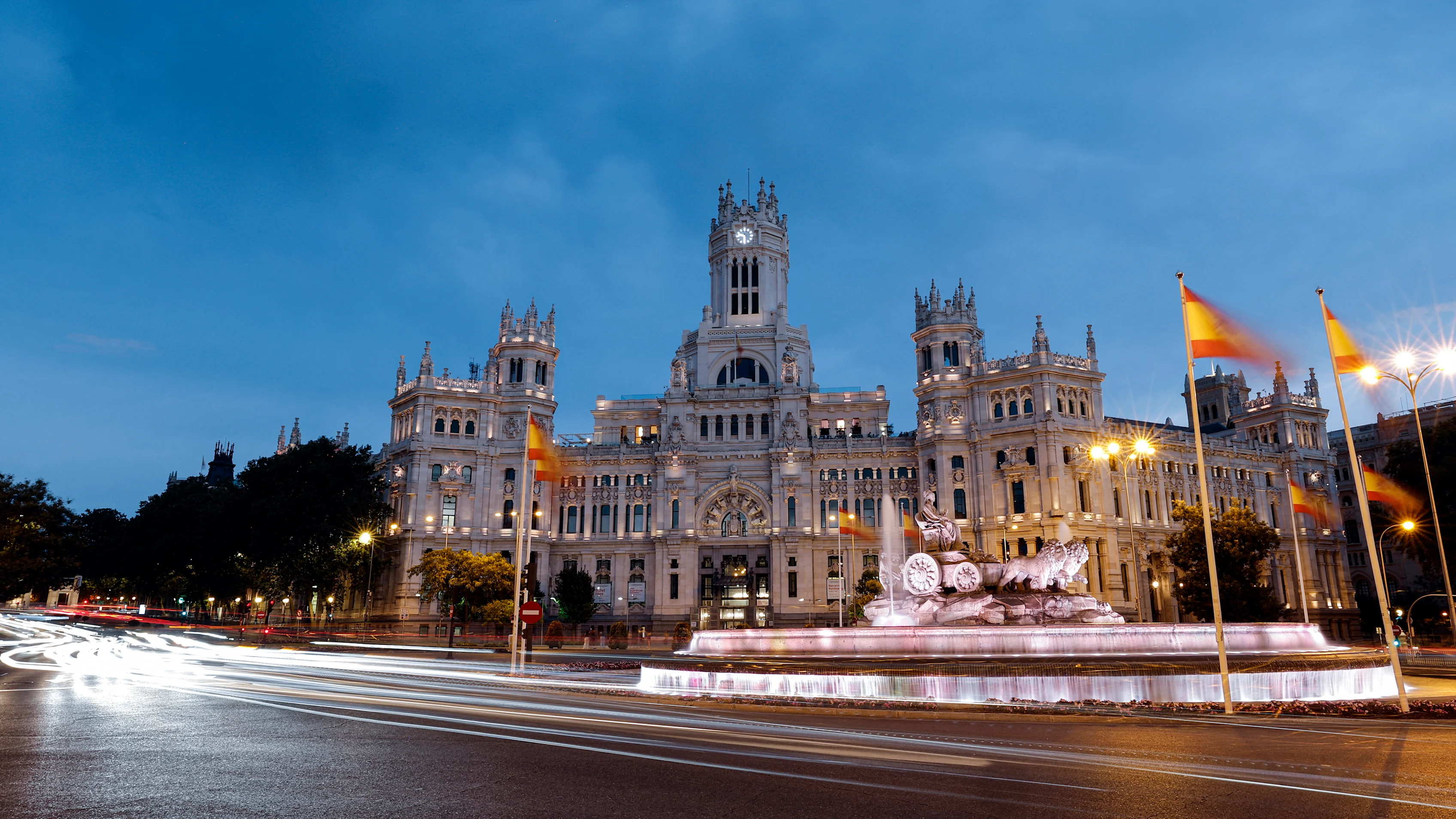 La vista general muestra el Cibeles Fountain y el Palacio Cibeles en Madrid iluminado al anochecer en julio