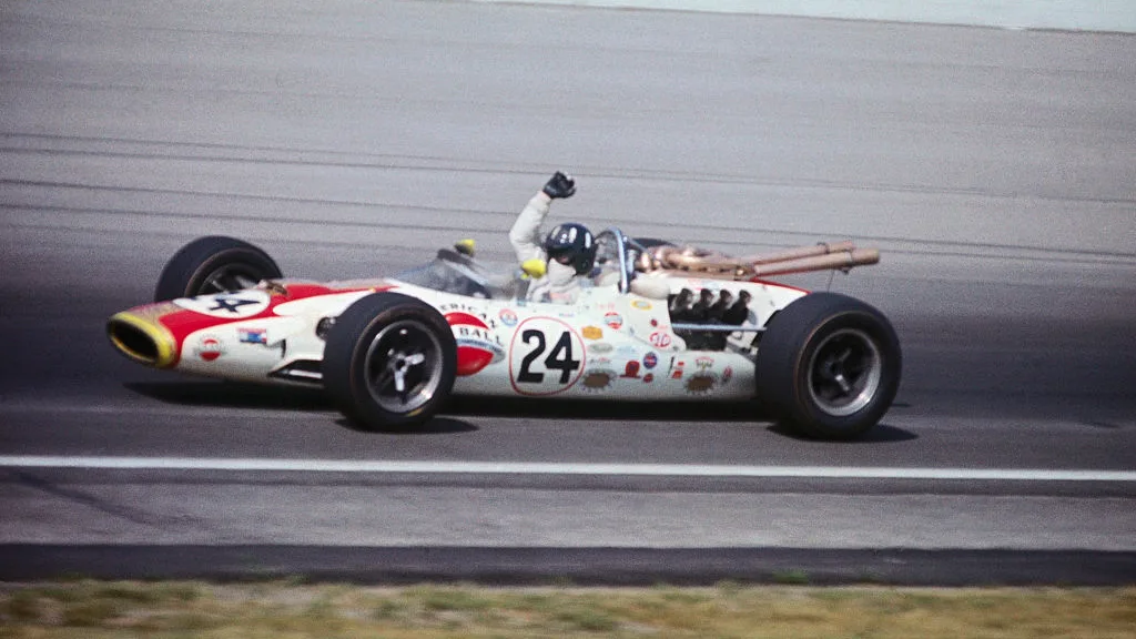 (Leyenda original) Graham Hill, con brazos levantados en la señal de victoria, dando vueltas después de ganar